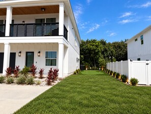 Une maison moderne à deux étages, dotée d’une pelouse bien entretenue et d’une clôture blanche.