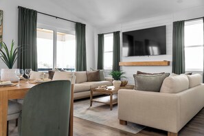 A modern living room with a sofa, coffee table, and a TV mounted on the wall. - Preserve Views | Game Room | Direct Beach Access (Saint Augustine)