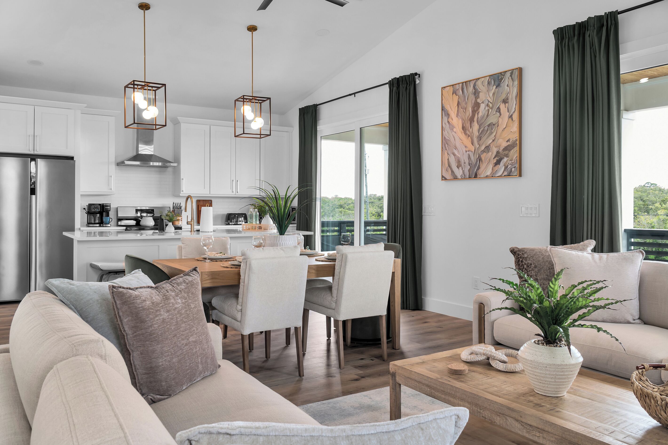 A modern living room with a sofa, a dining table, and a kitchen in the background.