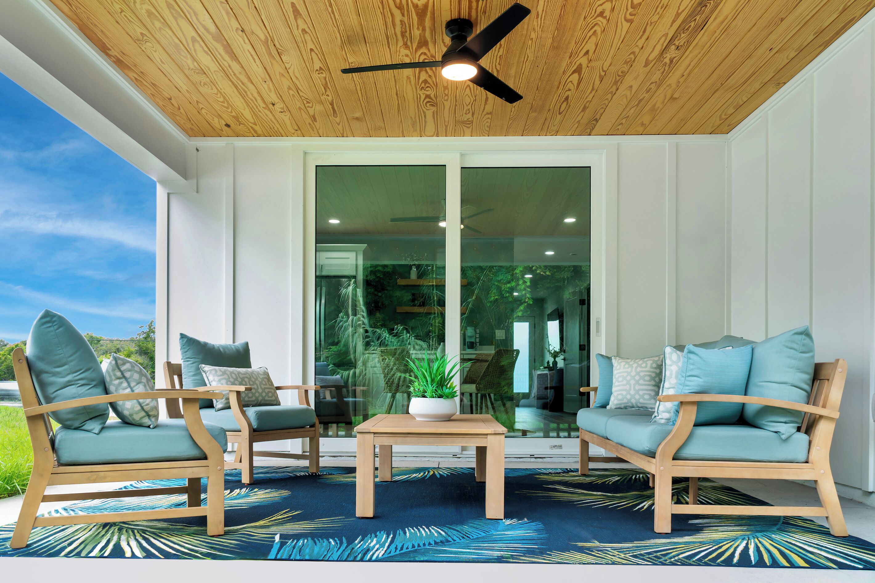 Un área de estar moderna al aire libre con mobiliario de madera y un ventilador de techo.