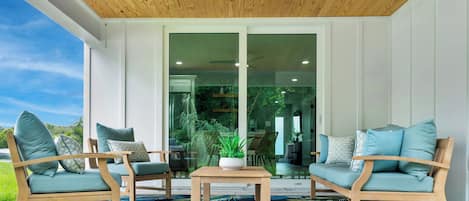 Un área de estar moderna al aire libre con mobiliario de madera y un ventilador de techo.