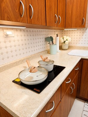 A kitchen with wooden cabinets, a countertop, a stove, and a backsplash with a geometric pattern.