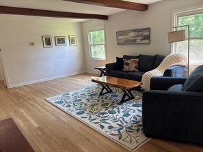 A living room with a sofa, a coffee table, a patterned rug, and a painting on the wall.