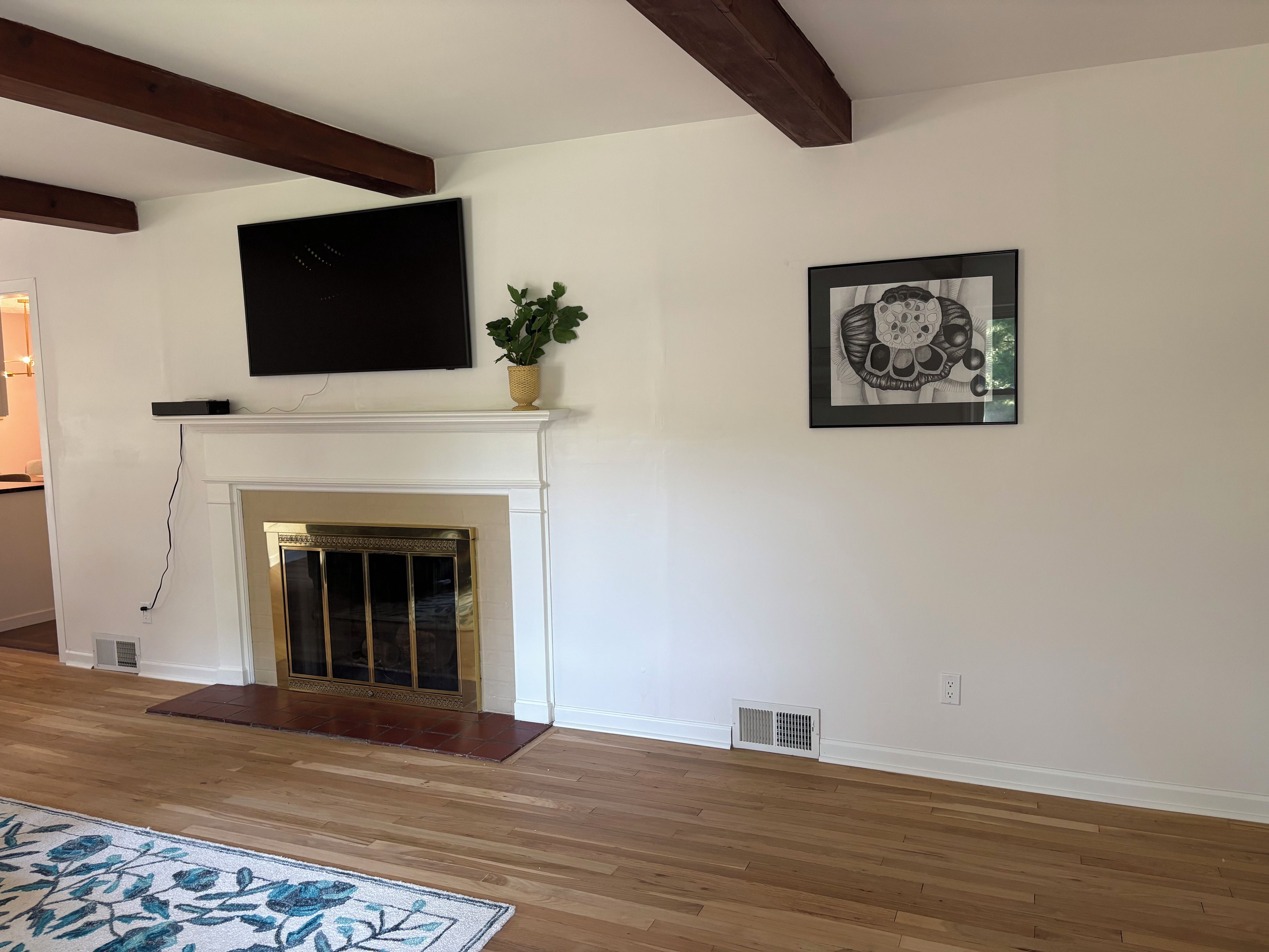 A room with a fireplace, a television mounted above it, and a framed artwork on the wall.