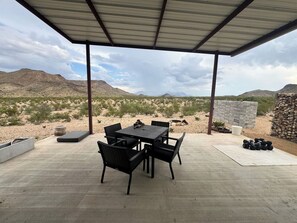 Eine Terrass mit Tisch und Stühlen, eine Steinsäule und Blick auf die Wüstenlandschaft.