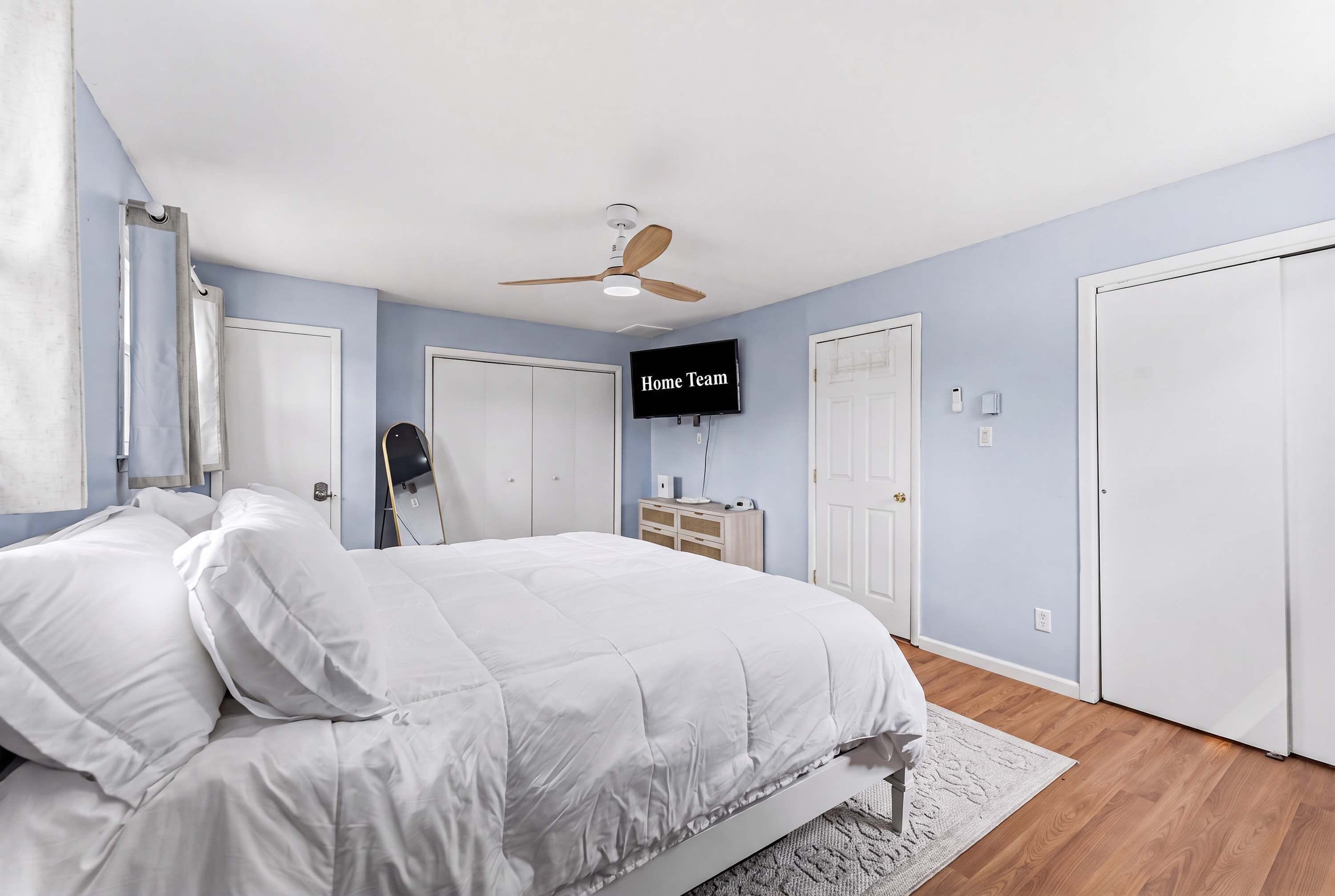 A bedroom with a bed, a ceiling fan, a TV, and a wardrobe.