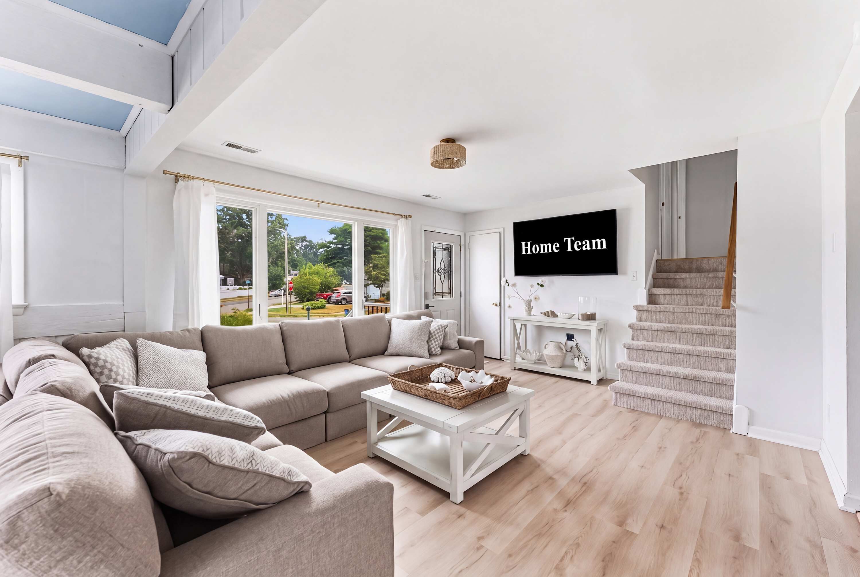 A modern living room with a sectional sofa, a coffee table, and a television displaying 'Home Team'.