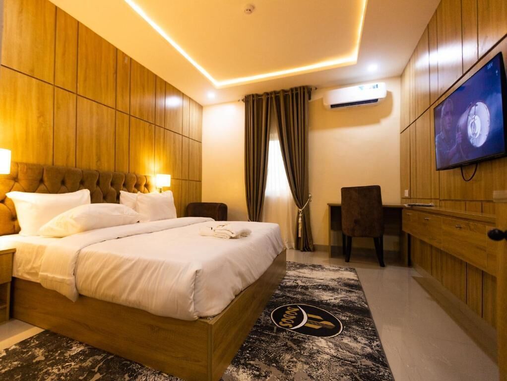 Una habitación de hotel con una cama grande, televisión, escritorio y una silla.