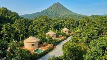 Un resort con yurtas circulares, una piscina y una montaña al fondo.