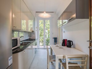 A modern kitchen with a dining area, a microwave, a kettle, and a coffee maker. - Gli Oleandri di Grazia by Interhome (Licciana Nardi)