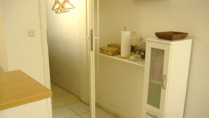 A narrow hallway with a white cabinet on the right, a wooden door on the left, and a shelf with various items above it. - Hamburg: 3-room apartment, 50 square meters, 3 beds, lodging, vacation rental—including LAST-MINUTE deals (Hamburg)