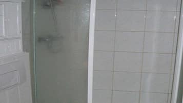 Un bany amb dutxa trencada per vidre, vàter i un rentapans.
