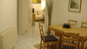 A dining area with a wooden table and chairs, a radiator, and a painting on the wall. - Hamburg: 3-room apartment, 50 square meters, 3 beds, lodging, vacation rental—including LAST-MINUTE deals (Hamburg)