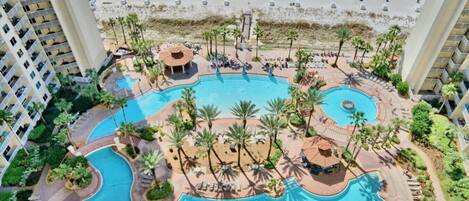 A resort with multiple swimming pools, palm trees, and a beach area.