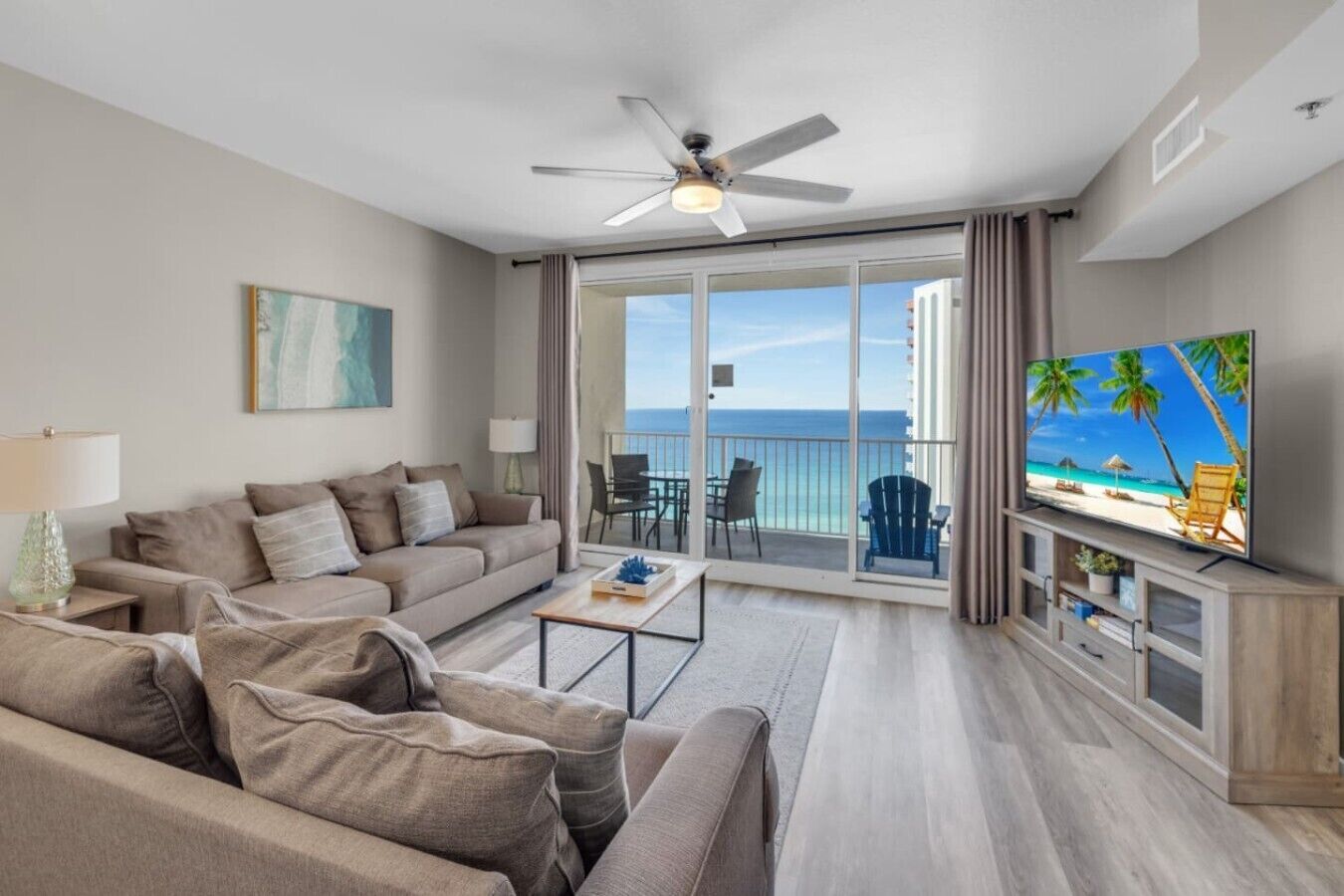 A modern living room with a sofa, coffee table, and a TV displaying a beach scene.