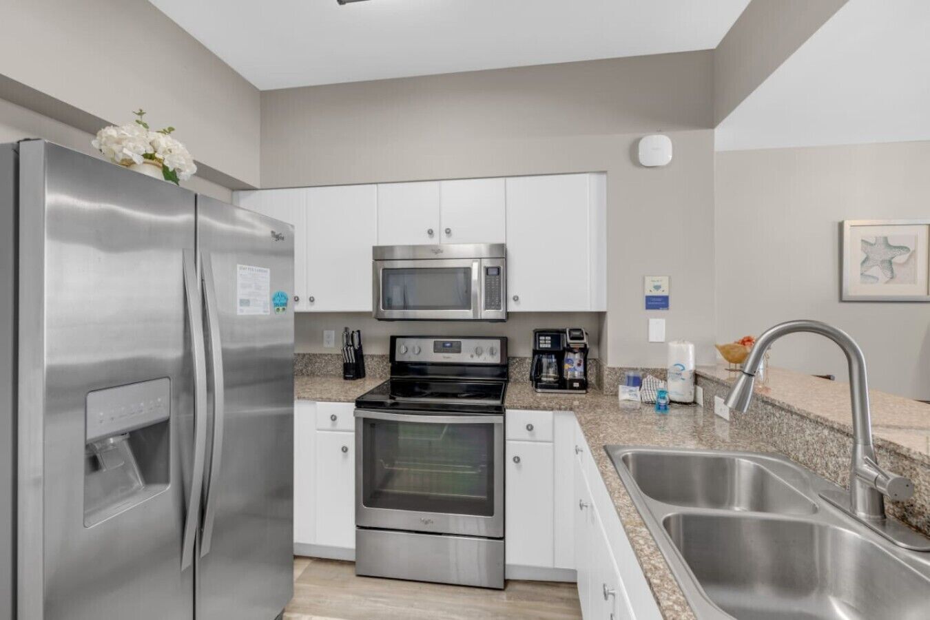 Una cocina moderna con electrodomésticos de acero inoxidable, armarios blancos y encimeras de granito.
