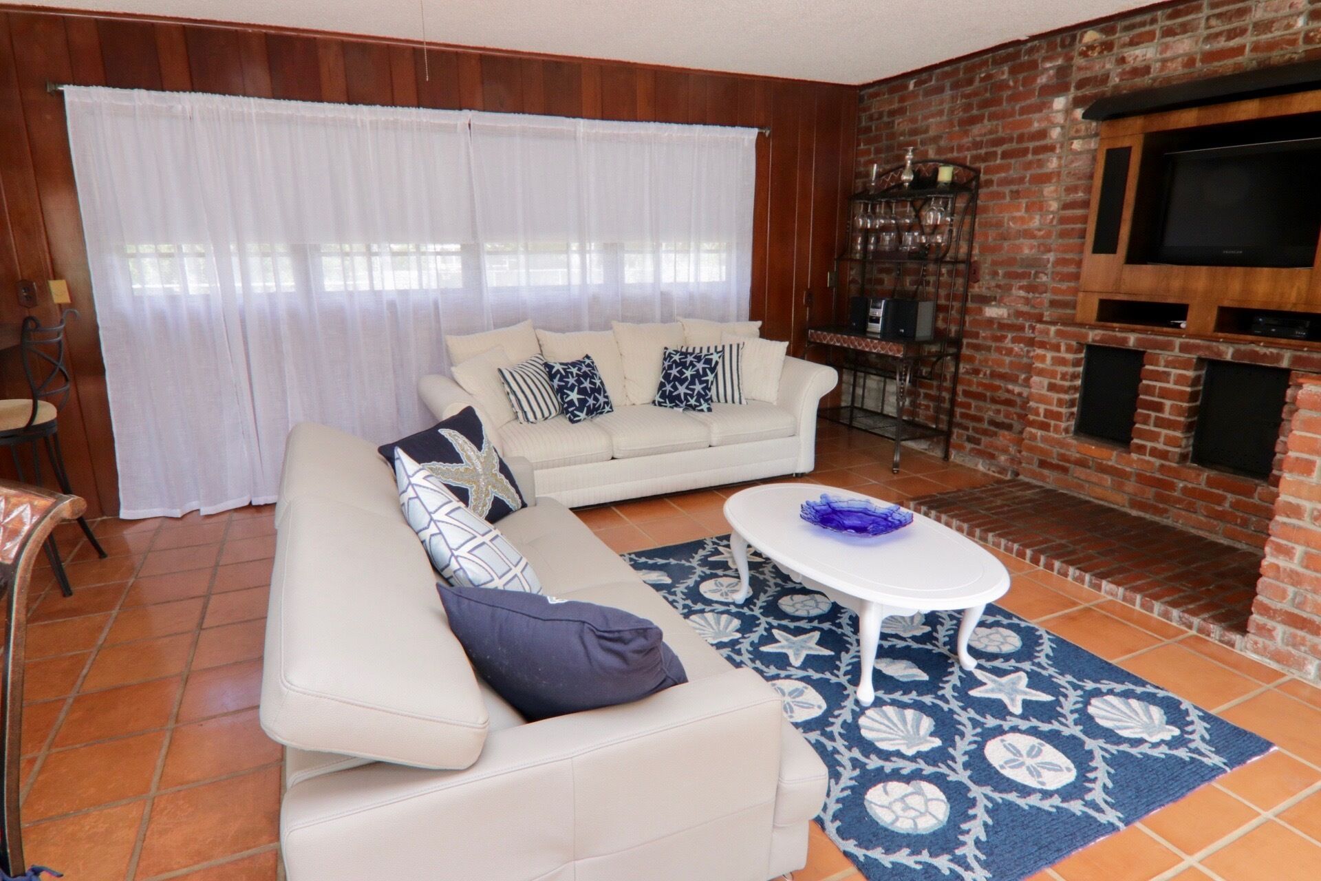 A living room with a sofa, coffee table, and a brick fireplace.