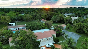 An aerial view of a residential area with multiple houses, a swimming pool, and lush greenery. - Historic Pool House on 4-acre Mango Farm in heart of Miami-Reduced this Summer (Miami)