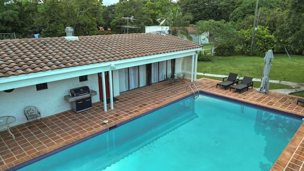 A swimming pool with a tiled deck, a barbecue grill, and outdoor furniture. - Historic Pool House on 4-acre Mango Farm in heart of Miami-Reduced this Summer (Miami)