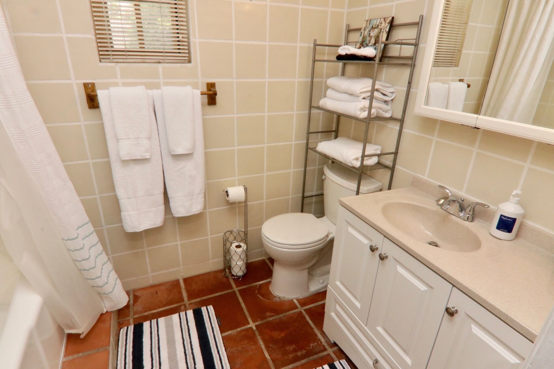 Ein Badezimmer mit Toilette, Waschbecken, Handtuchhalter und Duschvorhang.