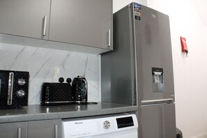 A kitchen with a stainless steel refrigerator, a Hisense dishwasher, and a coffee maker on the countertop. - Stylish Bradford Home | Near City Centre | Sleeps 11 (Bradford)
