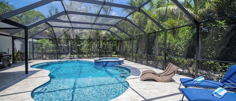 A covered outdoor swimming pool with lounge chairs and a barbecue area.
