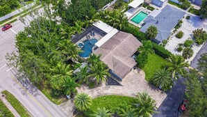 An aerial view of a residential area with a swimming pool, a covered patio, and lush greenery. - Heated Pool & Spa • 3 BRs • 10 min to Siesta Key (Sarasota)