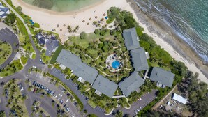 An aerial view of a resort with a central pool, multiple buildings, and a beach. - Beachfront 6BR, 2 Condos for 16 at Turtle Bay! (Kahuku)