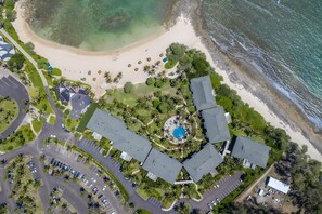 Eine Luftaufnahme eines Resorts mit einem zentralen Pool, mehreren Gebäuden und einem Strand.