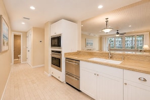 A kitchen with a granite countertop, stainless steel appliances, and a window with a view of buildings.