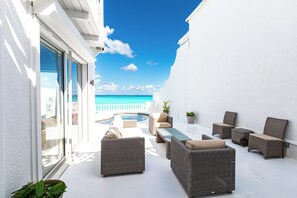 An outdoor patio with wicker furniture, a pool, and a view of the ocean. - Caprice 5 - 3BR Oceanfront Villa + Pool (Nassau)