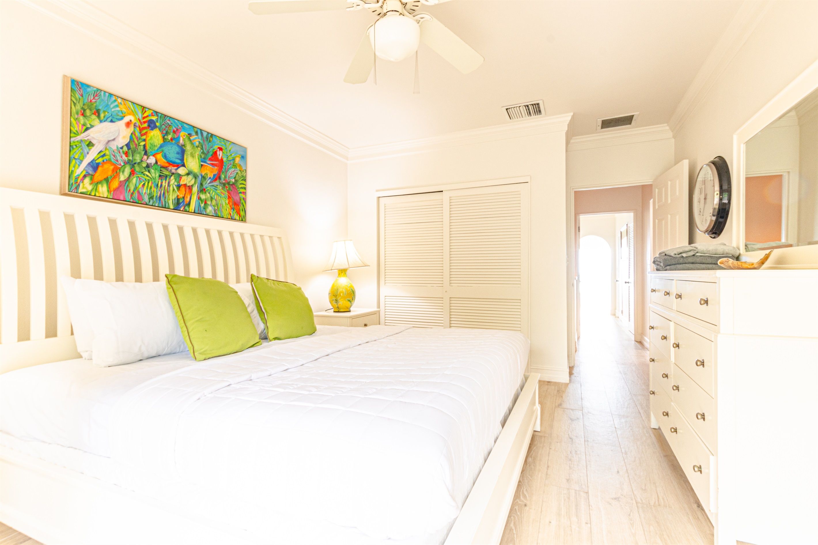 A bedroom with a bed, a nightstand, a lamp, a wardrobe, and a painting on the wall.