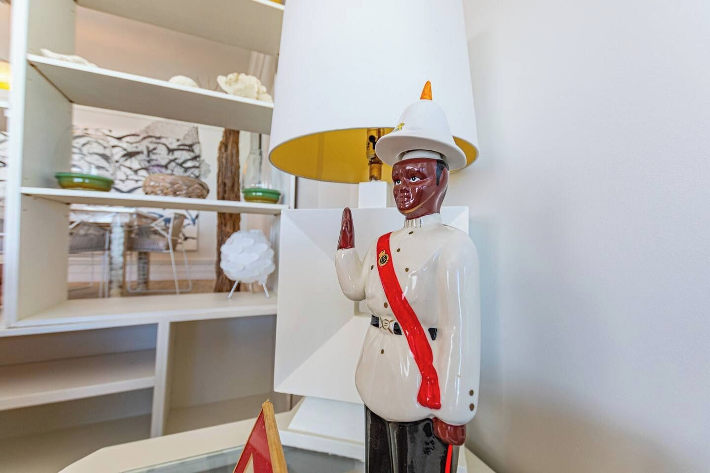 A room with a white lamp, a shelf with decorative items, and a statue of a figure in uniform.
