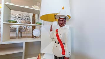A room with a white lamp, a shelf with decorative items, and a statue of a figure in uniform.