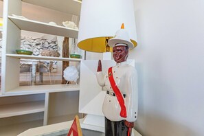 A room with a white lamp, a shelf with decorative items, and a statue of a figure in uniform. - Caprice 5 - 3BR Oceanfront Villa with Pool (Nassau)