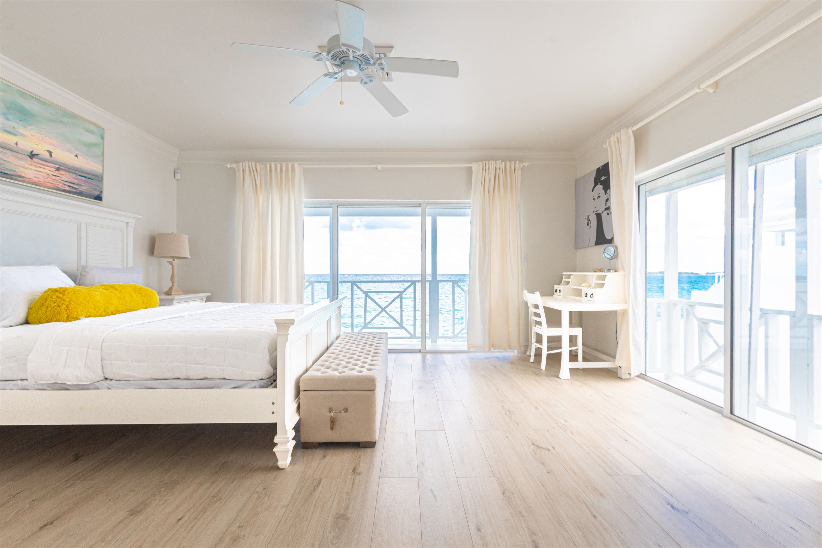 A bedroom with a bed, a bench, a desk, and a balcony with a view.