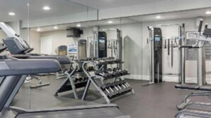 Un gimnasio con cintas de correr, máquinas de pesas y pesas libres.