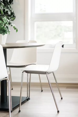 A modern dining area with a round table and two white chairs with chrome legs. - New Vineyard Cottage in Niagara Wine Country | 1BR (Lincoln)