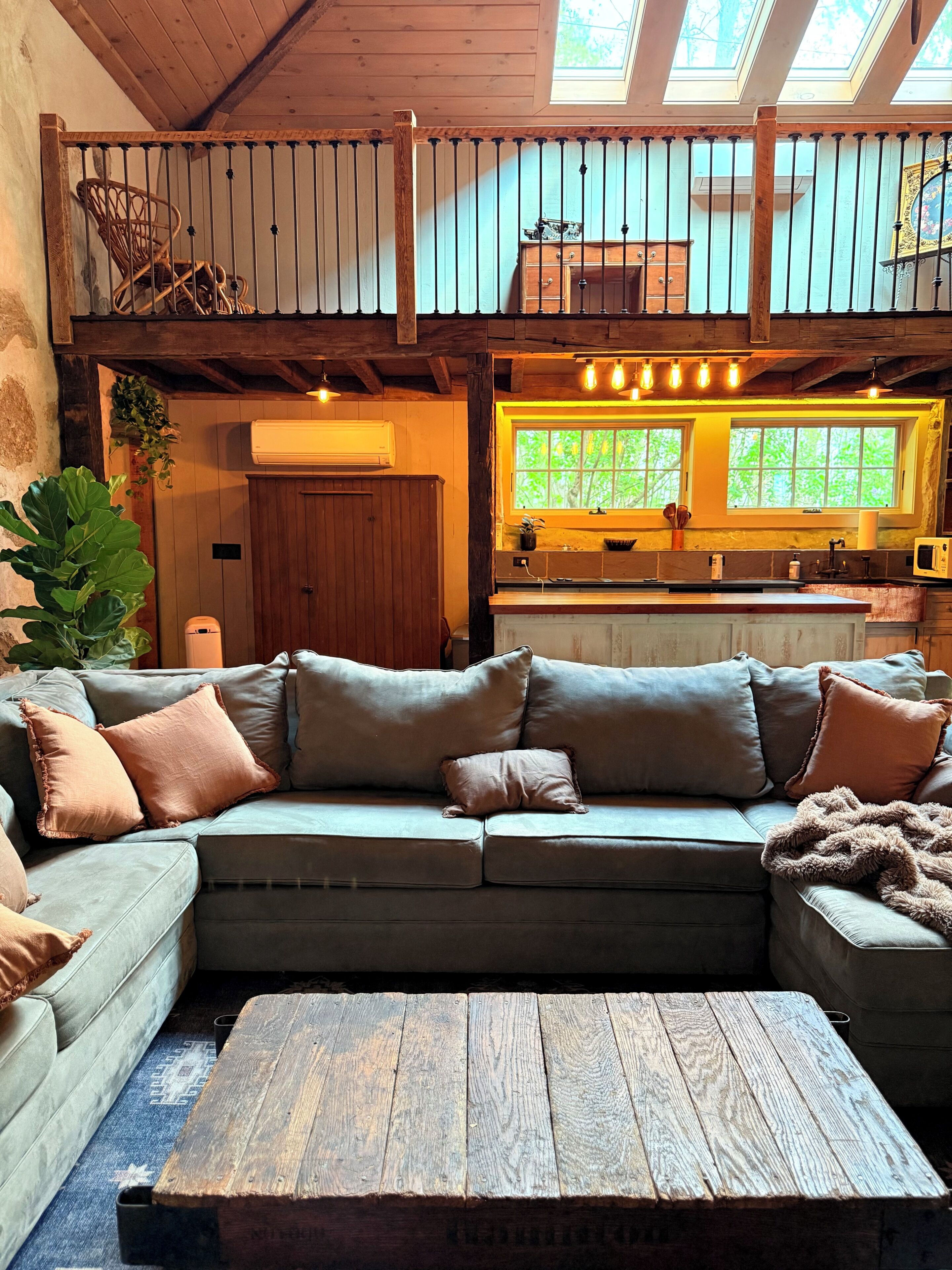A cozy living room with a sectional sofa, a wooden coffee table, and a balcony with a railing.