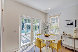 A dining area with a round table, yellow chairs, and a view of an outdoor pool through glass doors. - The Key West House | Tropical Oasis |Close 2 Beach (West Palm Beach)