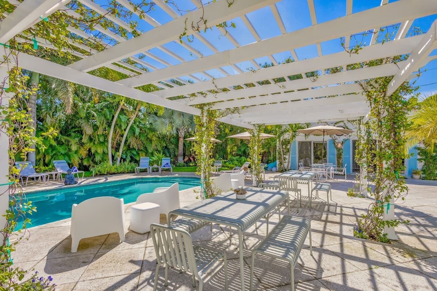 A poolside area with a pergola, lounge chairs, and a table with chairs.