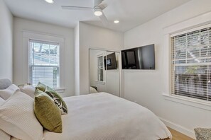 A bedroom with a bed, a ceiling fan, a flat-screen TV mounted on the wall, and a window with blinds. - The Key West House | Tropical Oasis |Close 2 Beach (West Palm Beach)