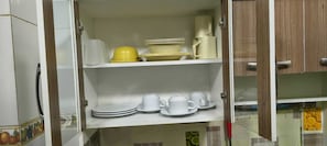 A kitchen with white cabinets, a yellow bowl, and white cups on the shelves.