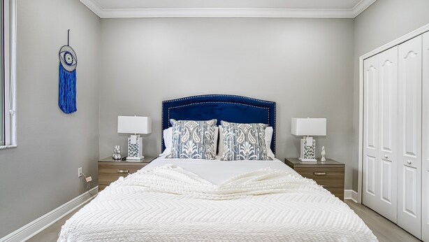 A bedroom with a large bed, two bedside tables, a wardrobe, and a dreamcatcher on the wall. - Private Oasis - Pool & Backyard (Hialeah)