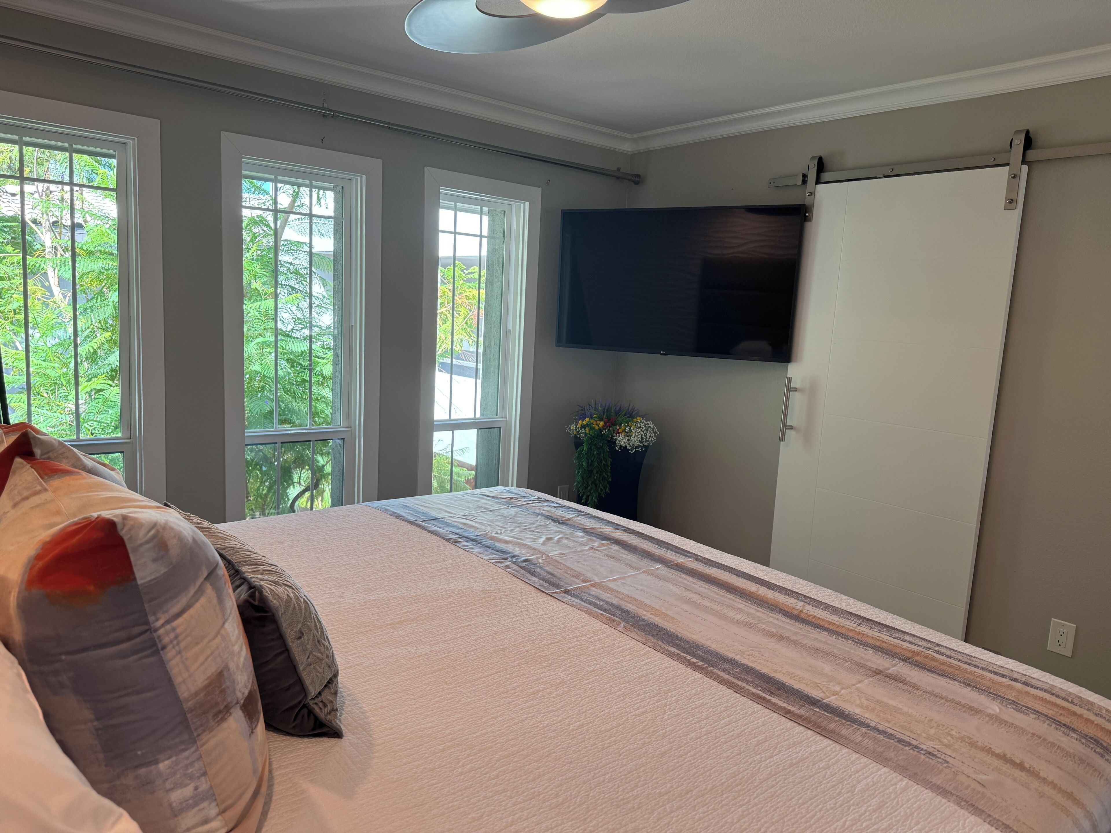 A bedroom with a bed, a television mounted on the wall, and a sliding door.