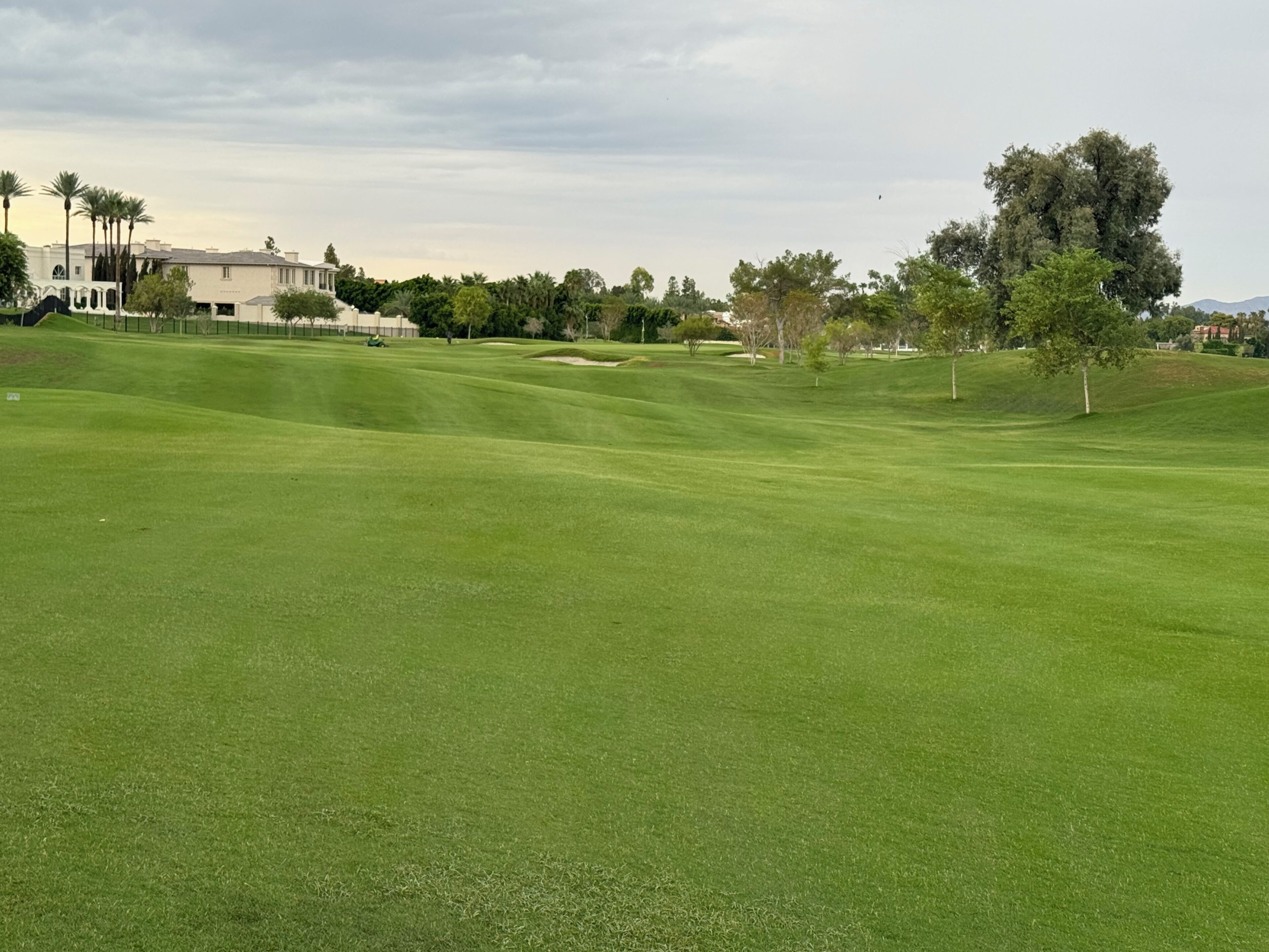 A well-maintained golf course with a clubhouse in the background.