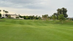 Ein gepflegter Golfplatz mit einem Clubhaus im Hintergrund.