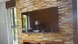 Eine Steinsäule mit integriertem Flachbildfernseher und Kamin darunter.