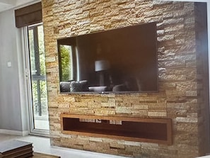 Eine Steinsäule mit integriertem Flachbildfernseher und Kamin darunter.