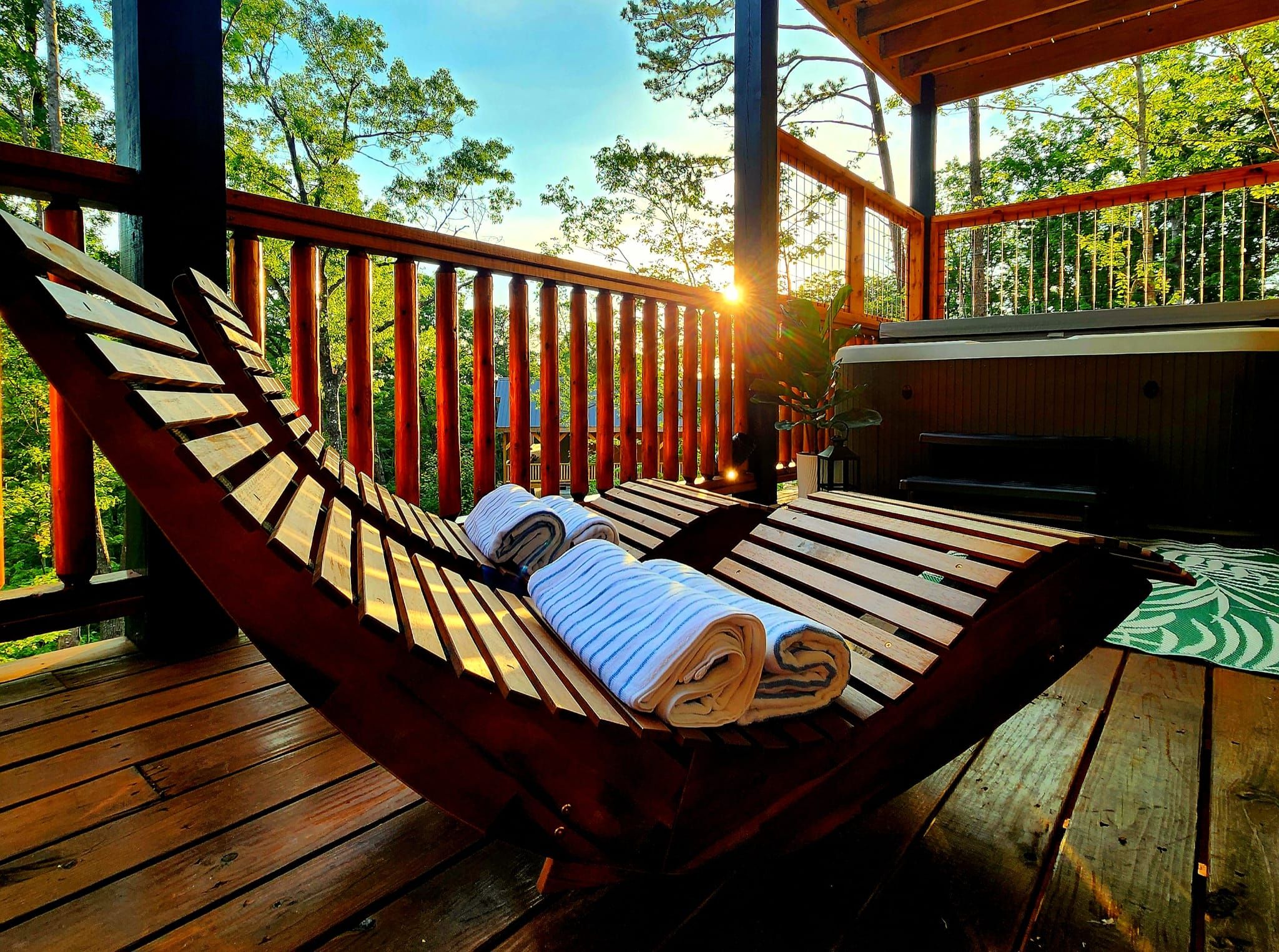 Un hamac sur une terrasse en bois, avec vue sur les arbres et un ciel dégagé.